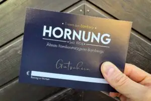 Gutschein der Metzgerei Hornung in Bamberg vor Holztür gehalten