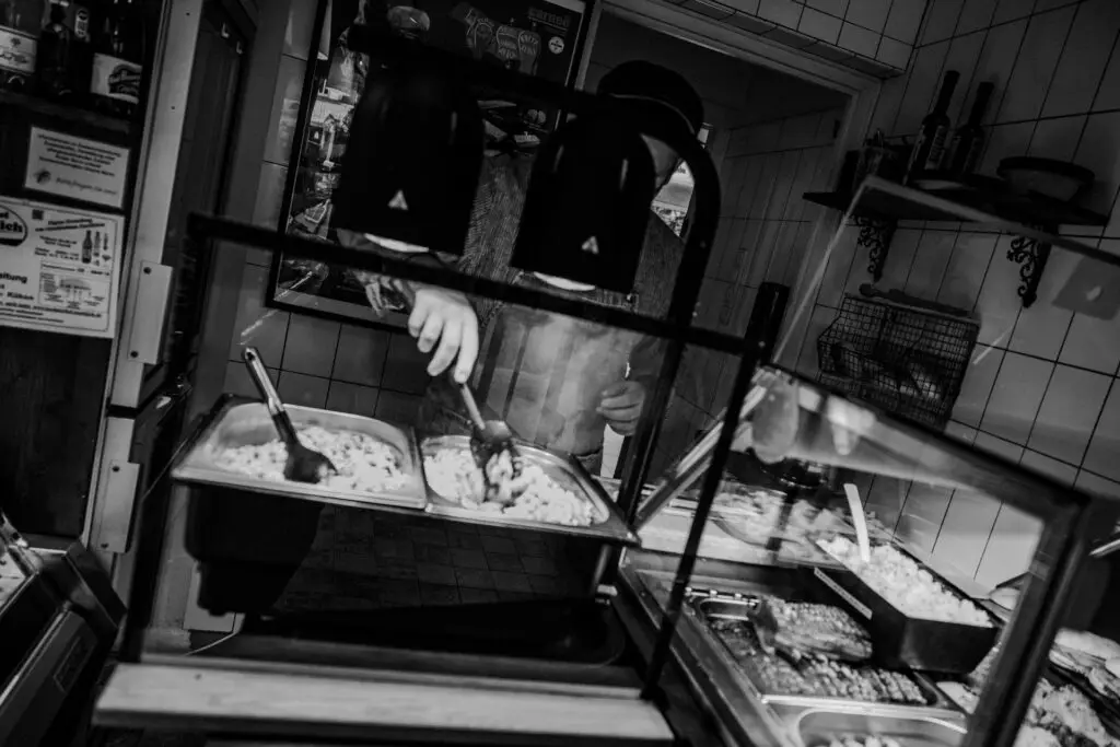 Handwerkliche Essensausgabe in der warmen Theke der Metzgerei Hornung in Bamberg, schwarz-weiß aufgenommen