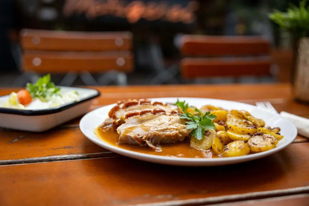 Hausgemachter Mittagstisch: Krustenbraten mit Bratkartoffeln und kleinem Marktsalat der Metzgerei Hornung Bamberg auf einem Biertisch im Innenhof serviert