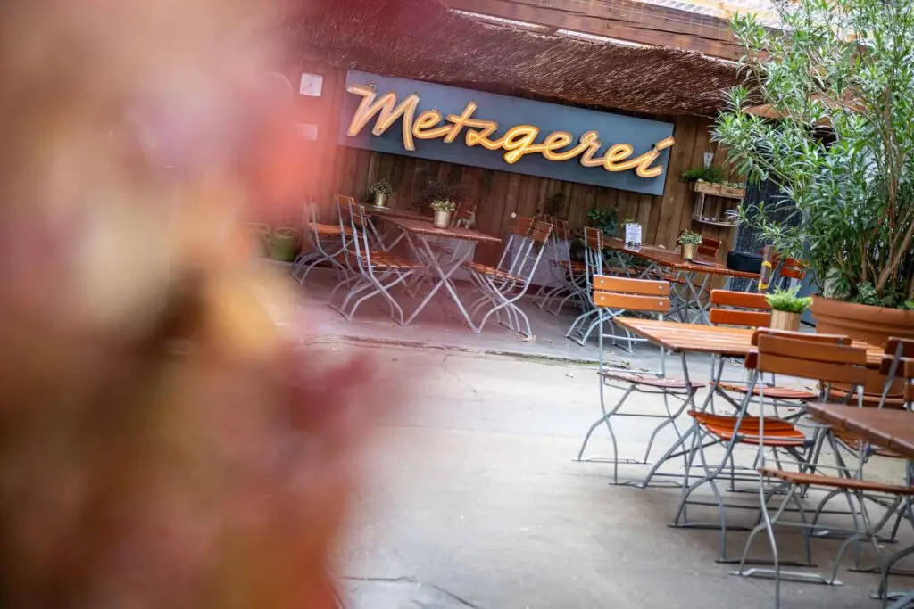Innenhof der Metzgerei Hornung Bamberg mit Sitzplätzen und alter Leuchtreklame "Metzgerei" im Hintergrund