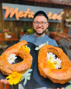 Mitarbeitender der Metzgerei Hornung Bamberg präsentiert zwei frisch gebackene Leberkäse in Zahlenform 6 und 0